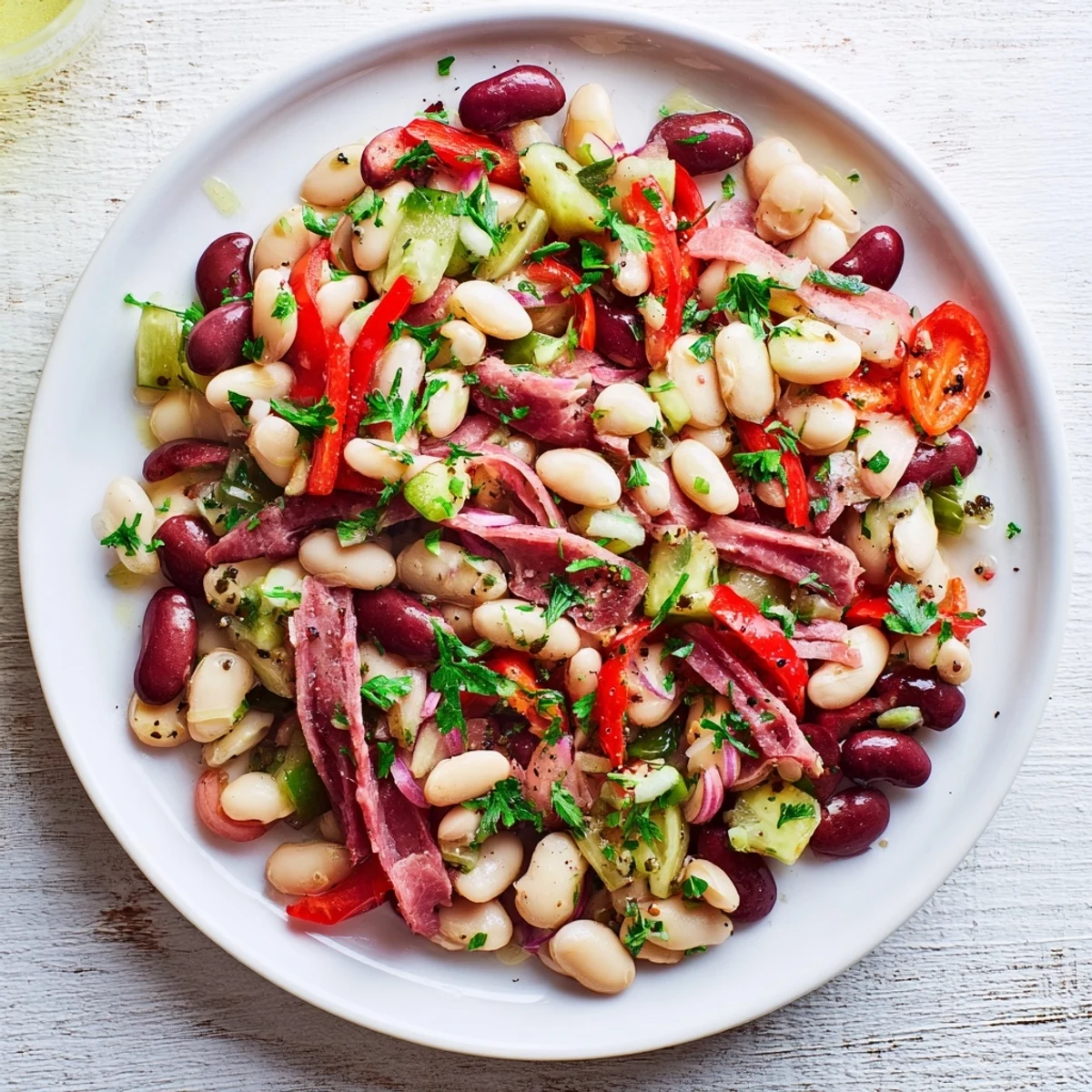 Hearty dense bean salad with prosciutto, vibrant colors, glistening with zesty vinaigrette, ready to eat.