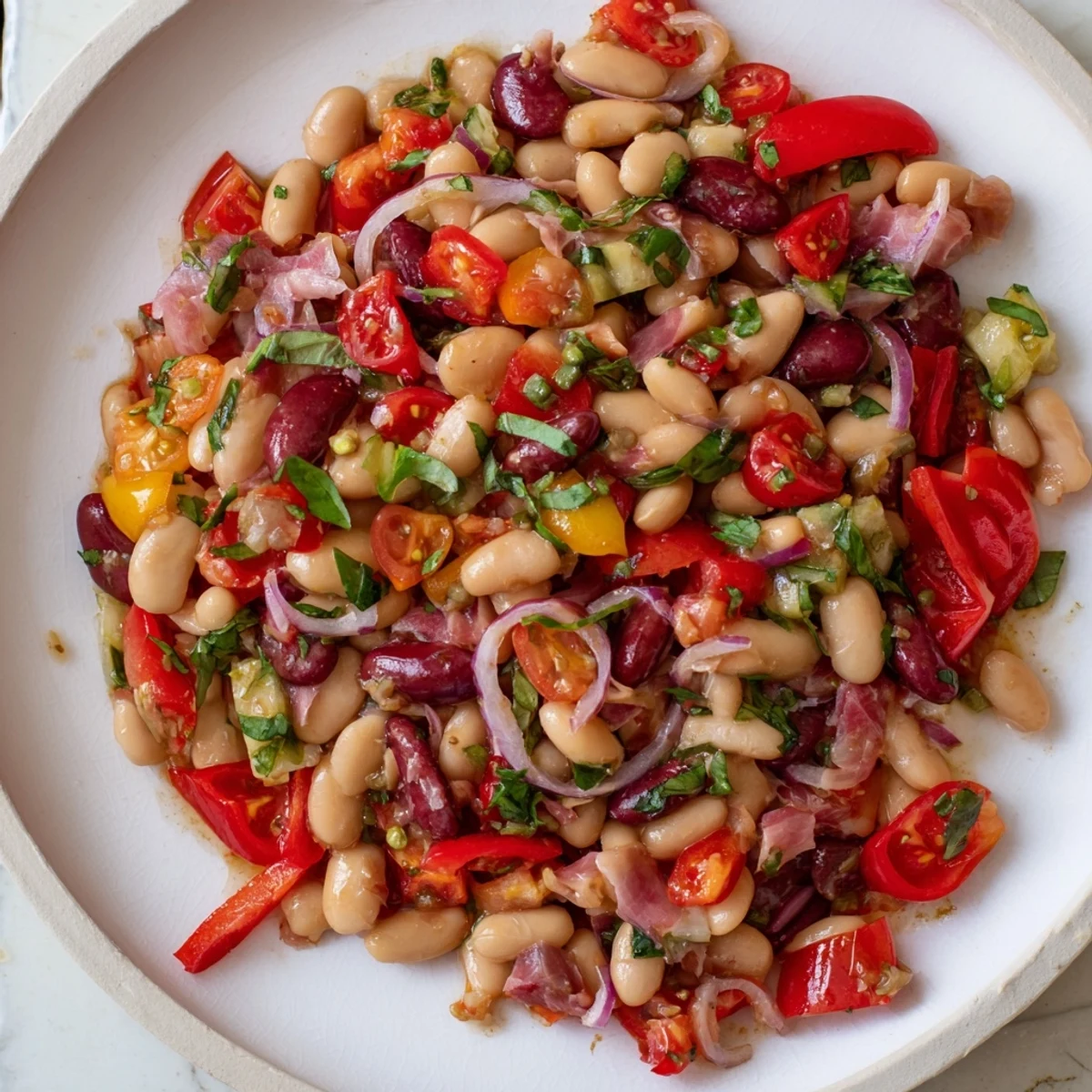 Close-up of a flavorful dense bean salad with prosciutto, featuring fresh herbs and a bright dressing.