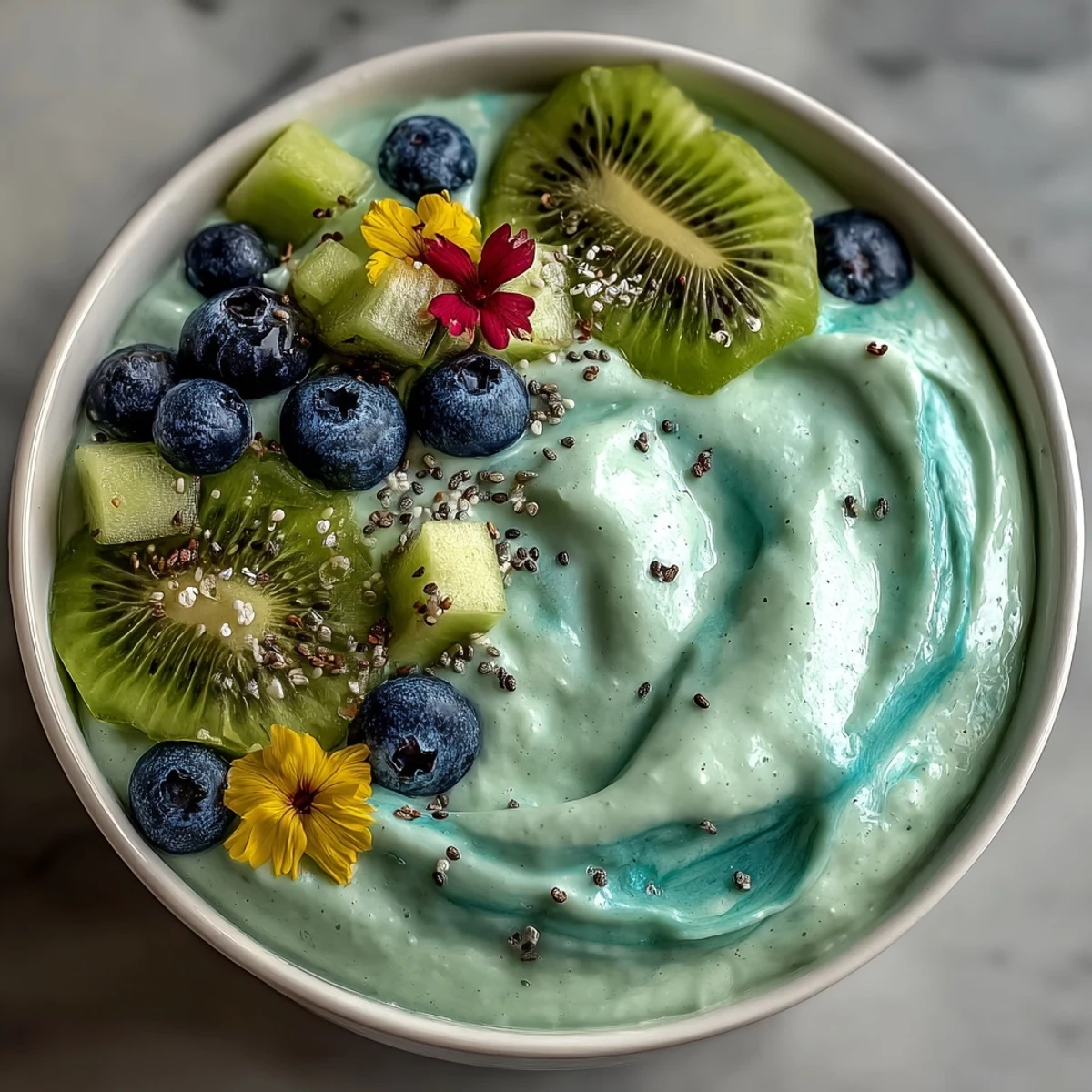 Vibrant blue Whimsical Healthy Mermaid Smoothie Bowl topped with kiwi slices, fresh blueberries, and dragon fruit for a whimsical breakfast.