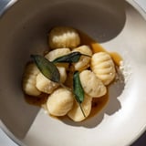 Golden, perfectly formed Homemade Potato Gnocchi, dusted with flour, waiting to be boiled and enjoyed.