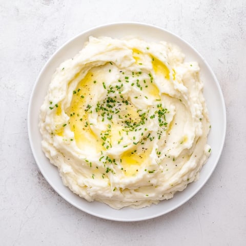 Close-up of Creamy Garlic Mashed Potatoes, fluffy, garnished with fresh chives, ready to serve and enjoy.