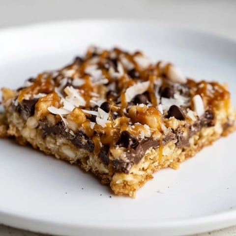 Gooey, layered 7-Layer Magic Bars topped with a shimmering salted caramel drizzle, ready to eat.