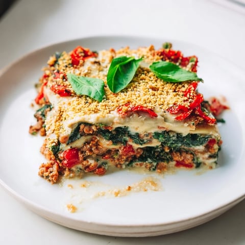 A warm, bubbling dish of vegan lasagna with savory mushroom-spinach bolognese and creamy topping.