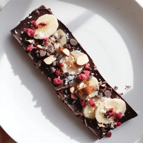 Rich, dark chocolate banana bark topped with almonds and berries, a refreshing frozen dessert.