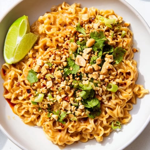 Steaming bowl of Instant Peanut Thai Sauce Noodles, garnished with fresh cilantro and crunchy peanuts.