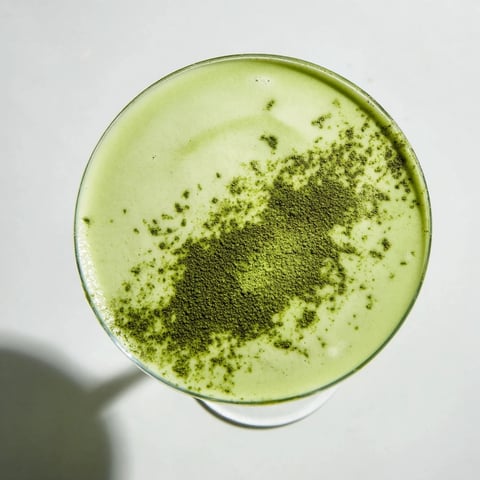 A frothy Matcha Martini cocktail in a chilled glass with vibrant green hue and creamy texture.  