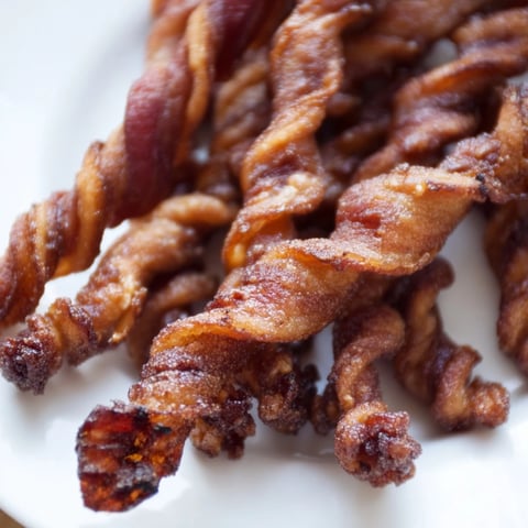 Crispy spiced bacon twists glistening with brown sugar and cinnamon on a wire rack, ready for brunch.  