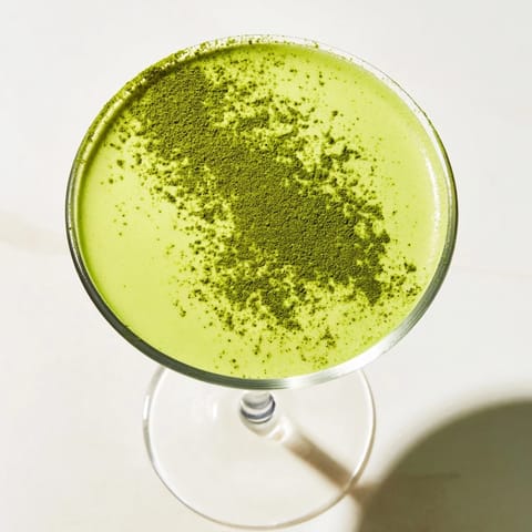 Matcha Martini garnished with white chocolate shavings, showing a smooth, velvety pour in a martini glass.  