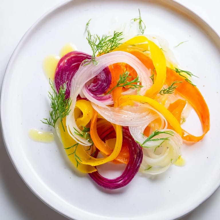 Vibrant The Spinning Top salad features wispy ribbons of fresh vegetables with herb garnish.
