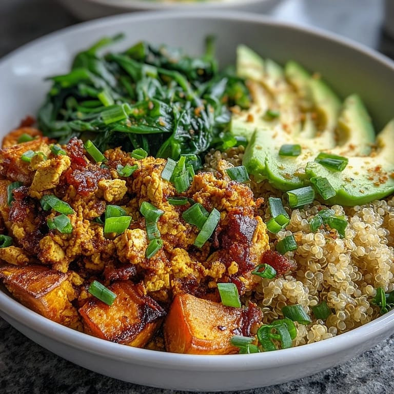 Wholesome vegan breakfast bowl with turmeric-spiced tofu scramble, tender roasted sweet potatoes, sautéed greens, quinoa, and creamy avocado.
