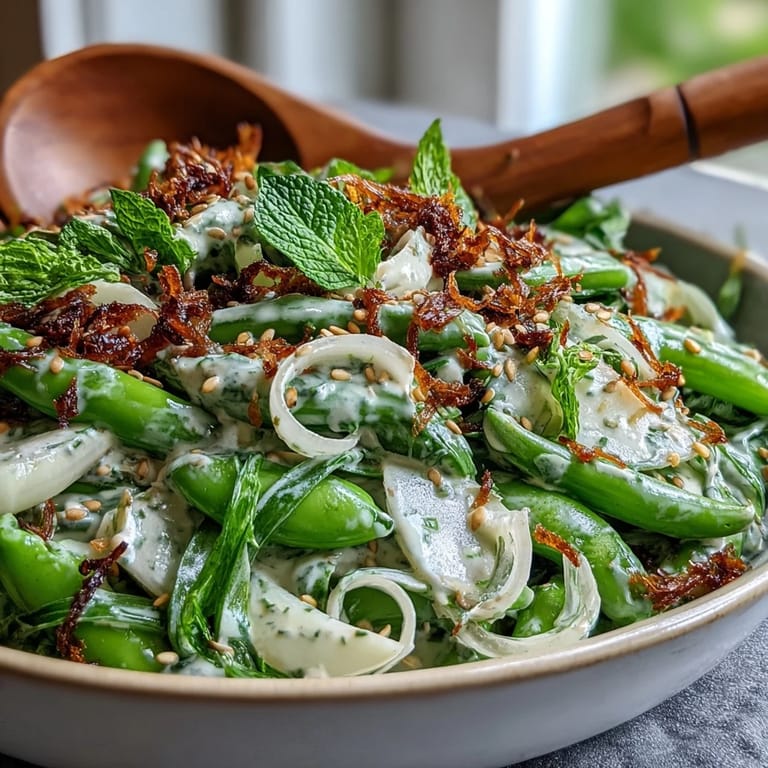 Crisp spring salad featuring snap peas, radishes, and herbs, tossed in a zesty lemon-tahini dressing.