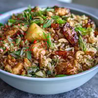 A colorful bowl of pineapple chicken fried rice with juicy pineapple chunks, tender chicken, and crunchy roasted cashews.  