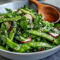 Fresh snap pea and radish salad with creamy tahini dressing, vibrant greens, and toasted sesame seeds for crunch.